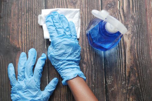 hand in blue rubber gloves holding spray bottle .