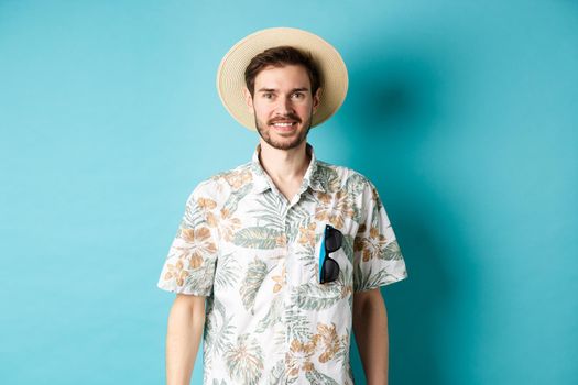 Happy and positive tourist in hawaiian shirt and straw hat, smiling at camera. Concept of tourism and summer holiday.