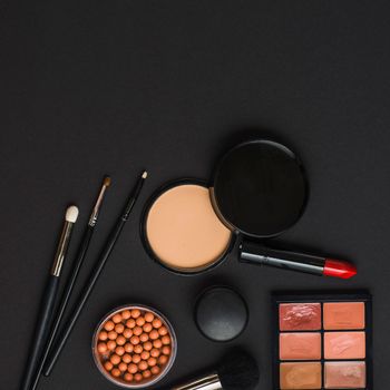 overhead view makeup products with brushes black backdrop. High resolution photo