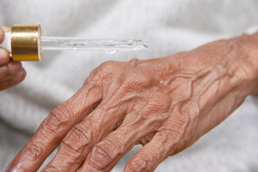 senior women applying essential oils on hand ,