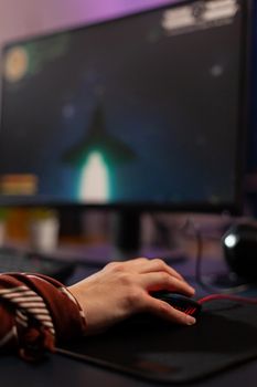 Close up of gamer using mouse during live space shooter tournament in gaming home studio. Pro gamer streaming online videogames using technology network wireless