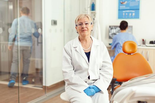 Portrait of specialist doctor working in stomatological office room preparing for dentistry surgery during sick man patient orthodontic consultation. Medical nurse analyzing tooth x-ray