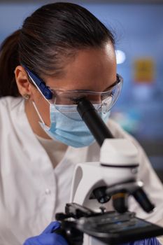 Woman with medical researcher occupation in laboratory working on microscope testing dna sample for development. Professional biochemist worker using medical equipment for treatment innovation