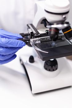 Close-up of doctor woman hands analyzing microbiology disease test results using medical microscope. Specialist researcher working at pharmaceutical expertise in pharmaceutical hospital laboratory