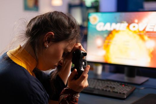 Professional gamer keeping her controller on hand after losing space shooter game using wireless joystick . Competitive player using modern equipment for online championship