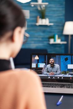 Caucasian female chatting with her math teacher during university videocall conference using laptop cumputer. Student working at communication lesson while sitting at desk in living room