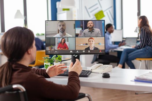 Handicapped paralyzed invalid employee during virtual meeting talking on videocall working from start up business office discussing with partners online using webcam. Businesswoman on video conference.