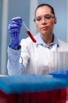 Scientist researcher looking at blood test tube researching scientific biology expertise in discovery laboratory. Specialist chemist working at microbiology experiment discovering disease infection