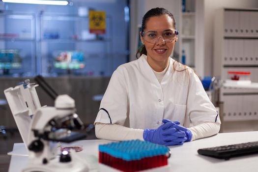 Scientific woman sitting in laboratory with tools preparing for research development experiment. Biotechnology worker with glasses for protection and lab coat analyzing innovation discovery