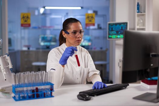 Medicine research scientist doing experiment on blood sample in flask at technology laboratory. Biochemistry woman working to test for treatment science innovation. Analysis development