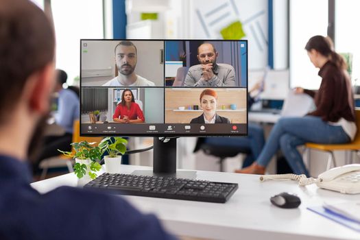 Paralysed handicapped businessman sitting immobilized in wheelchair having videomeeting discussing online with remotely colleagues in business office. Invalid employee working in financial company.