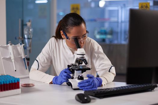 Medicine researcher woman working with microscope in chemical laboratory at medical clinic. Professional analysis worker using biotechnology equipment for discovery treatment development