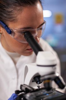 Experiment scientist analyzing sample on microscope in chemical research laboratory. Woman with chemist occupation working for developing vaccine treatment innovation at medical clinic