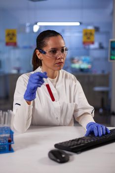 Biotechnology doctor in laboratory testing blood sample in tube for chemical discovery. Scientific research woman working for modern innovation development professional experiment