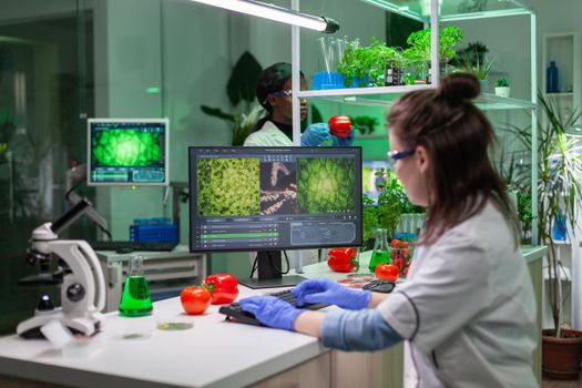 Scientist woman researcher typing biochemistry expertise on computer for microbiology experiment. Medical team working in pharmaceutical laboratory analyzing genetic mutation.