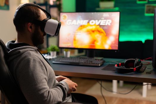 Videogame player losing space shooter competition while wearing virtual reality headset. Defeated gamer using professional console for online tournament late at night in gaming room