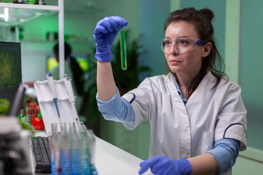 Chemist looking at test tube with geneticaly modified liquid for biology experiment. Biologist scientist researching chemical dna while working biochemistry agronomy laboratory.