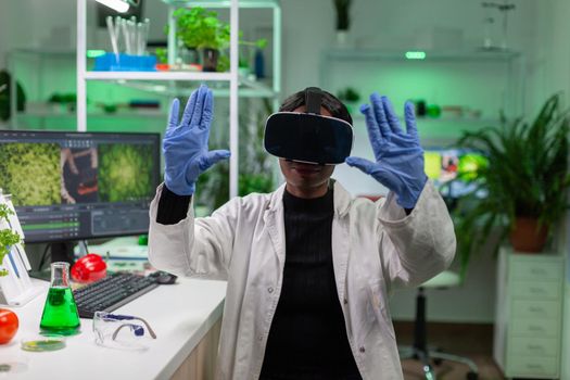 African scientist biologist conducting research using virtual reality doing hand gesture for agronomy looking at sample. Medical team working in pharmaceutical laboratory analyzing dna test.