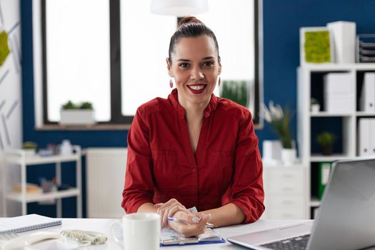 Portrait of cheerful happy excited business leadership smiling looking at camera. Entrepreneur with financial charts on clipboard on office desk in corporate workplace .