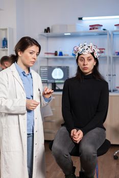 Female patient who is in a neurology clinic and her brain is being scanned. Woman sitting in lab equipped for development of experiments. Neuroscientist looking for brain trauma, nervous system.