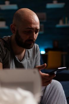 Frustrated, worried depressed man looking at unpaid bank bills notification received on smartphone. Disappointed, loneliness, anxiety, annoyed male reading digital eviction notice