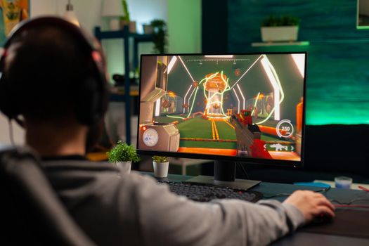 Pro gamer playing virtual shooter game for online competition using professional headphones. Online streaming cyber performing during gaming tournament using technology network wireless