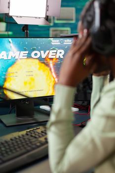 Afro esport player suffering lose defeat during space shooter live tournament. Professional gamer streaming online video games with new graphics on powerful computer.