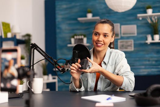 Influencer blogger smiling at camera while recording mouse review for followers. New media star on social media making video with professional equipment for online internet podcast show.