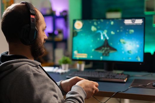 Videogamer playing graphics cyberspace sitting on gaming chair using technology network wireless. Man streaming viral videogames for fun using headphones and joystick for online championship