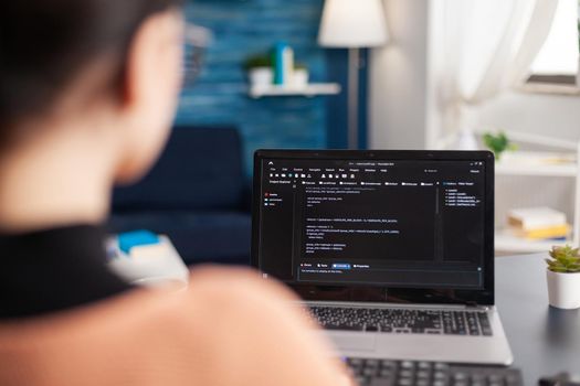 Young programmer writing virtual program code for software development and mobile application on laptop computer, Student programming javascript while sitting at desk table in living room