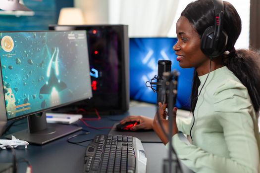 Pro afro american gamer talking into microphone for space shooter video tournament Streaming viral video games for fun using headphones and keyboard for online championship.