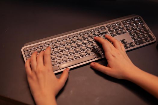 Close up hands shot of gamer pushing the keyboard buttons while playing online shooter video game. Virtual championship in cyberspace, esports player performing on pc during gaming tournament.