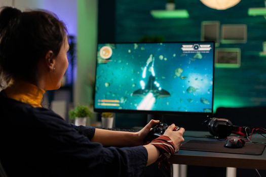 Caucasian woman holding wireless joystick and playing virtual videogames. Virtual streaming cyber performing live tournament using professional equipment in gaming home studio