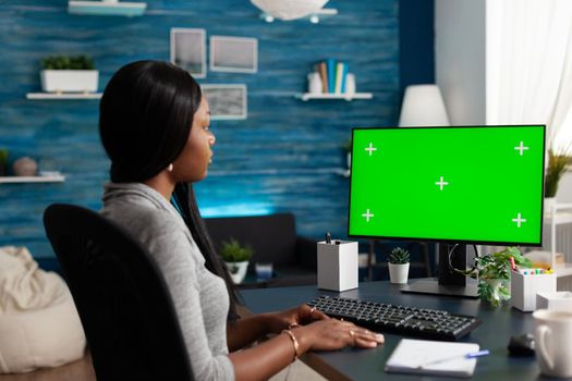 Black student discussing university courses during online videocall meeting conference looking at mock up green screen chroma key computer with isolated display. African woman working remote from home