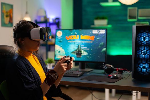 Competitive gamer looking into powerful computer playing online shooter game late at night with vr headset and console wireless. Virtual online streaming cyber performing during game tournament