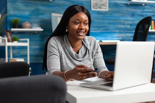 African american student making online sale shopping holding economy credit card in hands doing electronic payment on laptop computer. Black woman using internet banking service at home