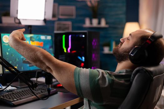 Excited player winning important online esport competition of space shooter playing on powerful computer. Professional pro gamer streaming videogames using professional microphone and headset