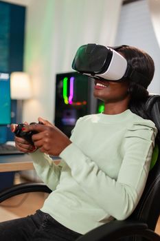 African professional gamer playing with wireless controller and vr headset. Virtual space shooter game championship in cyberspace, esports player performing on pc during gaming tournament.