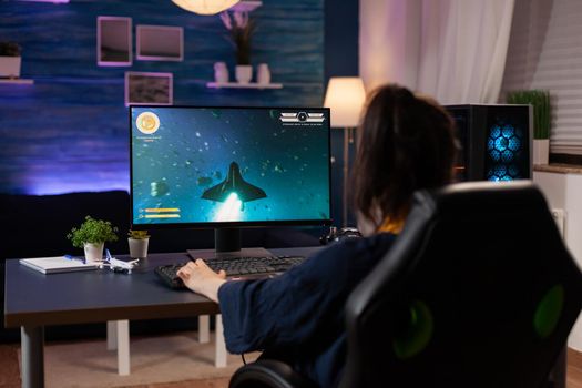 Focused player sitting on gaming chair in home studio and playing online videogames using RGB keyword. Professional pro player streaming online video game new graphics using powerful computer