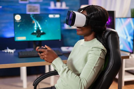 Professional esport player with vr headset using wireless joystick. Virtual space shooter game championship in cyberspace, esports player performing on pc during gaming tournament.