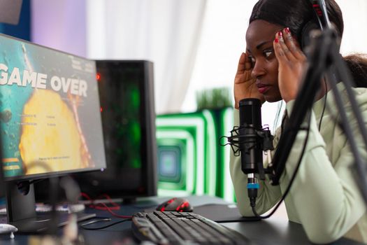 African streamer regrets losing live shooter game tournament touching temple. Professional gamer streaming online video games with new graphics on powerful computer.