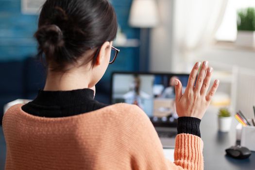 Student chatting with university collegue during online webinar using laptop computer, Young woman having remote education during coronavirus quarantine while sitting in living room