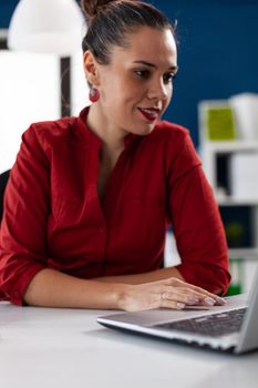 View of businesswoman typing on laptop and using touchped, in corprate business workplace building. Manager looking through documents in start up company. Director checking notest on notebook.