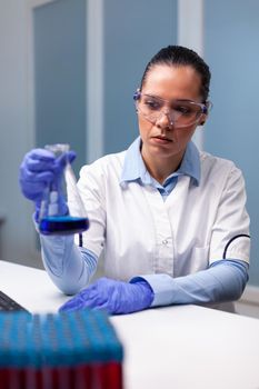 Scientist woman researching microbiology disease solution analyzing medical liquid using flask glass. Researcher doctor working at medicine biochemistry experiment in pharmacy hospital laboratory