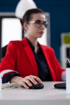 Focus on hand of businesswoman holding computer mouse working in corporate office. Entrepreneur clicking on device with wireless connection doing financial analysis. Close up shot of woman on mouse.