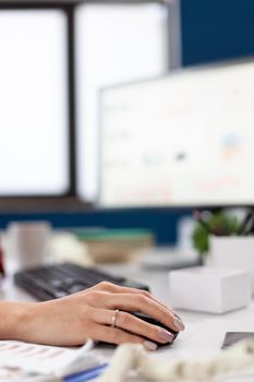 Company executive in his office using and clicking on mouse with bluetooth. Finger of hand pushing on mouse while entrepreneur is reading statistics, on computer screen in workplace .