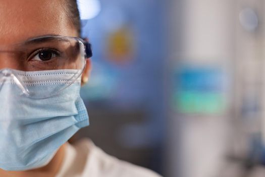 Portrait of biotechnology chemist working in laboratory at medical hospital. Woman with scientist occupation wearing protection glasses, face mask and lab coat industry equipment