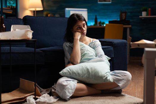 Portrait of depressed, vulnerable stressed desperate woman looking in camera sitting alone on couch feeling emotionally traumatised , physical desperate, suffering from anxiety, chronic disease