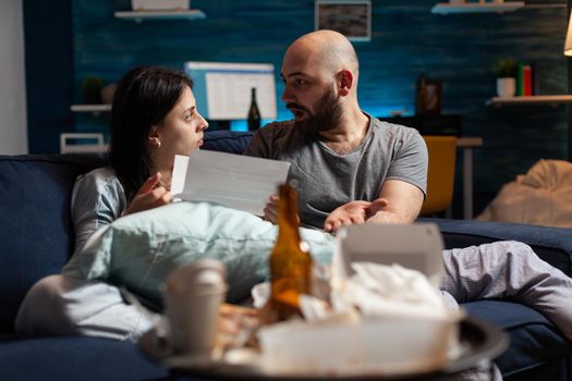 Depressed couple feeling sadness stressed about high mortgage rates, worried tenants by warning notification for unpaid renter bank bills. Woman reading eviction notice document