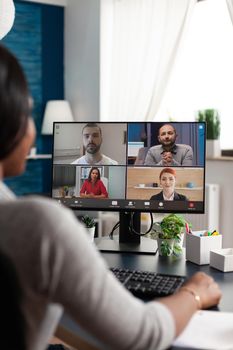 African american student discussing high school ideas with college team having online teleconference meeting conference in living room. Black woman working remote from home at academic project